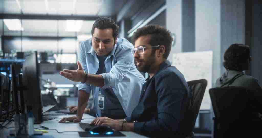 creative-team-of-indian-specialists-having-a-conversation-at-a-workplace-next-to-computer-two-male-software-engineers-discussing-a-software-code-for-their-digital-blockchain-development-project